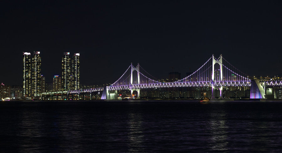 Gwangan Bridge lit in purple at night with Marine City towers glowing beside it