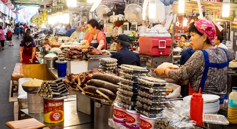 にぎわう韓国の伝統市場の屋台で、スンデやキンパを用意する店主