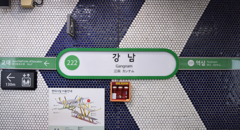 青と白のタイル壁に掛かるソウル地下鉄2号線・江南駅の駅名標