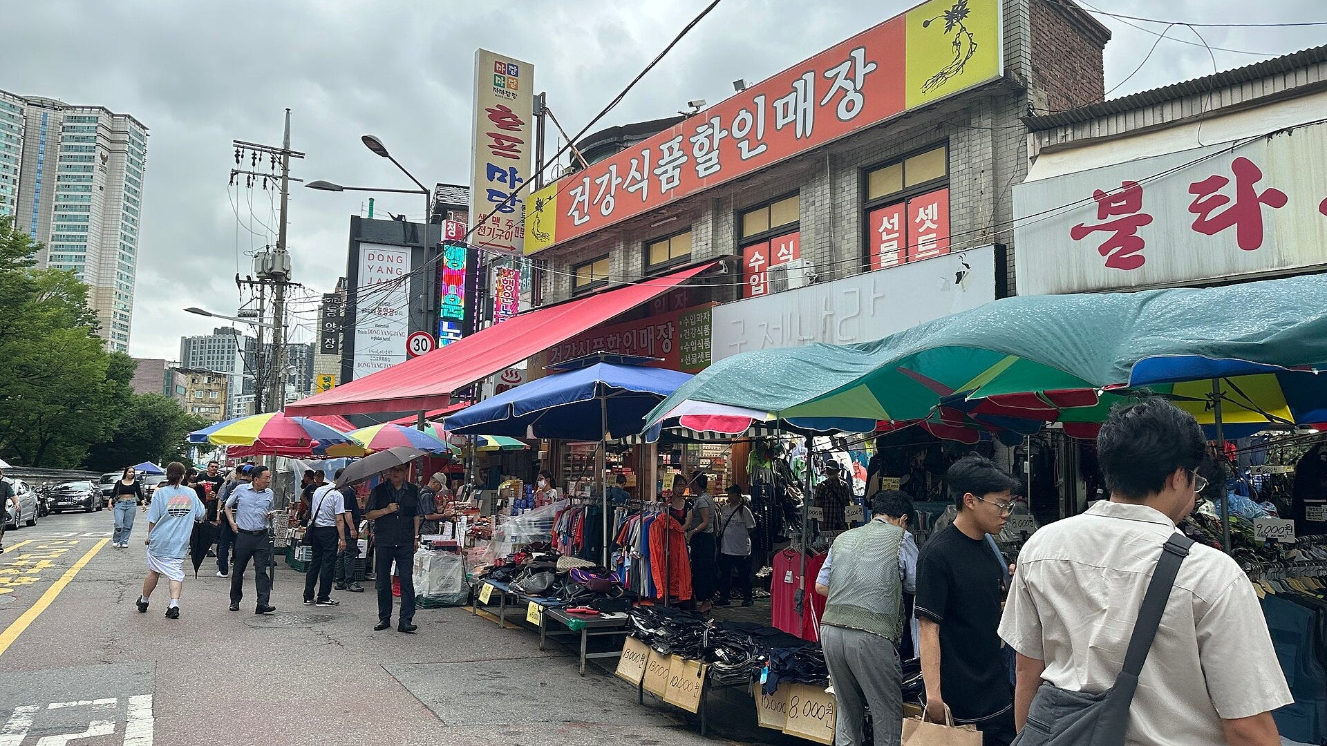 Dongmyo Flea Market street in Seoul lined with colorful umbrellas, secondhand clothing stalls and shoppers