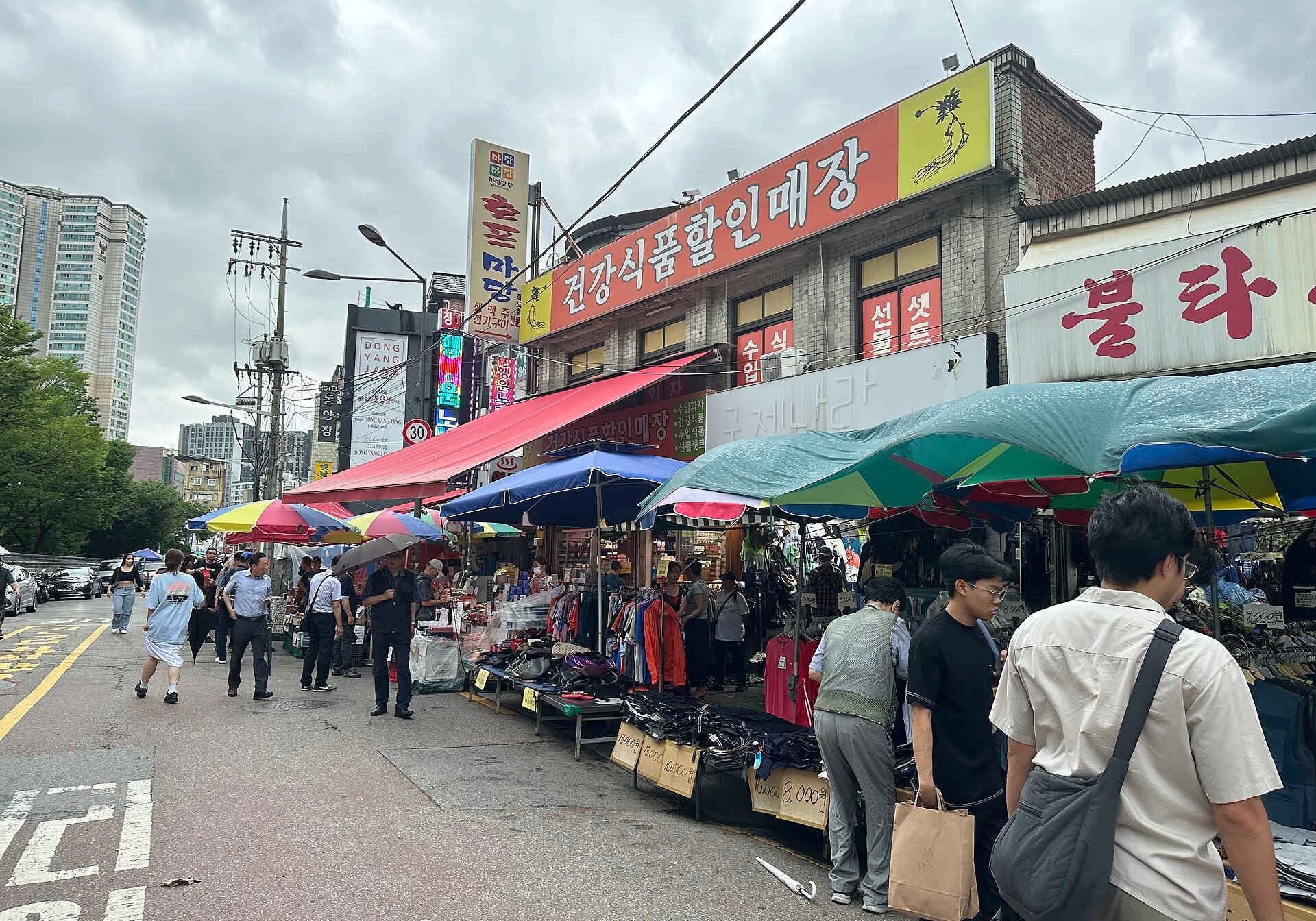 Dongmyo Flea Market street in Seoul lined with colorful umbrellas, secondhand clothing stalls and shoppers