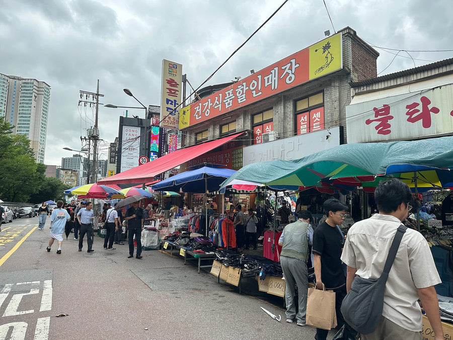Dongmyo Flea Market street in Seoul lined with colorful umbrellas, secondhand clothing stalls and shoppers