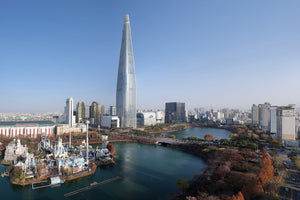 Autumn trees ringing Seokchon Lake below Lotte World Tower in Seoul on a clear late-November day