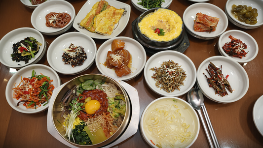 Overhead view of a Korean meal with rice, soup and many small side dishes covering a wooden table