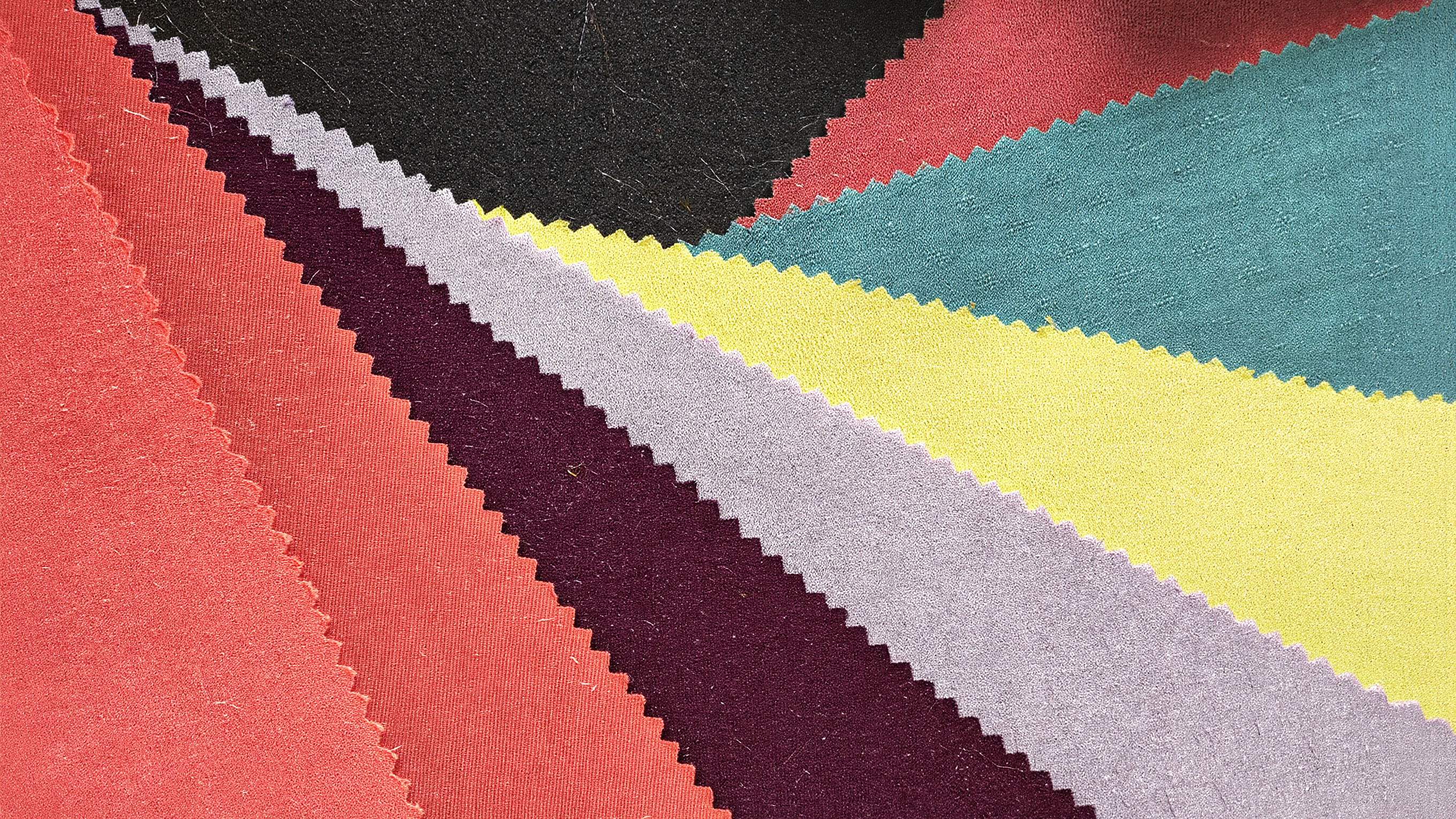 Personal color analysis fabric swatches fanned in coral, butter yellow, teal and deep berry in soft daylight