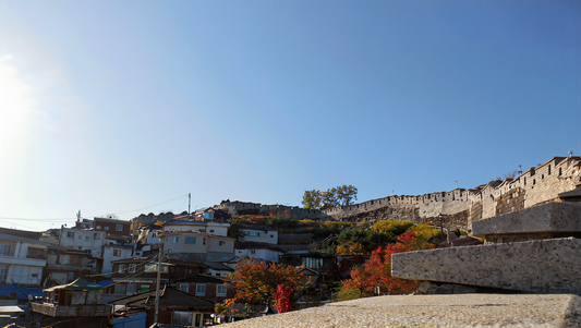 The old Seoul city wall along a ridge above hillside houses under a clear blue autumn sky