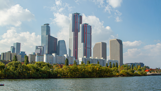 Yeouido skyline rising above green riverside trees on the Han River in bright early-September daylight