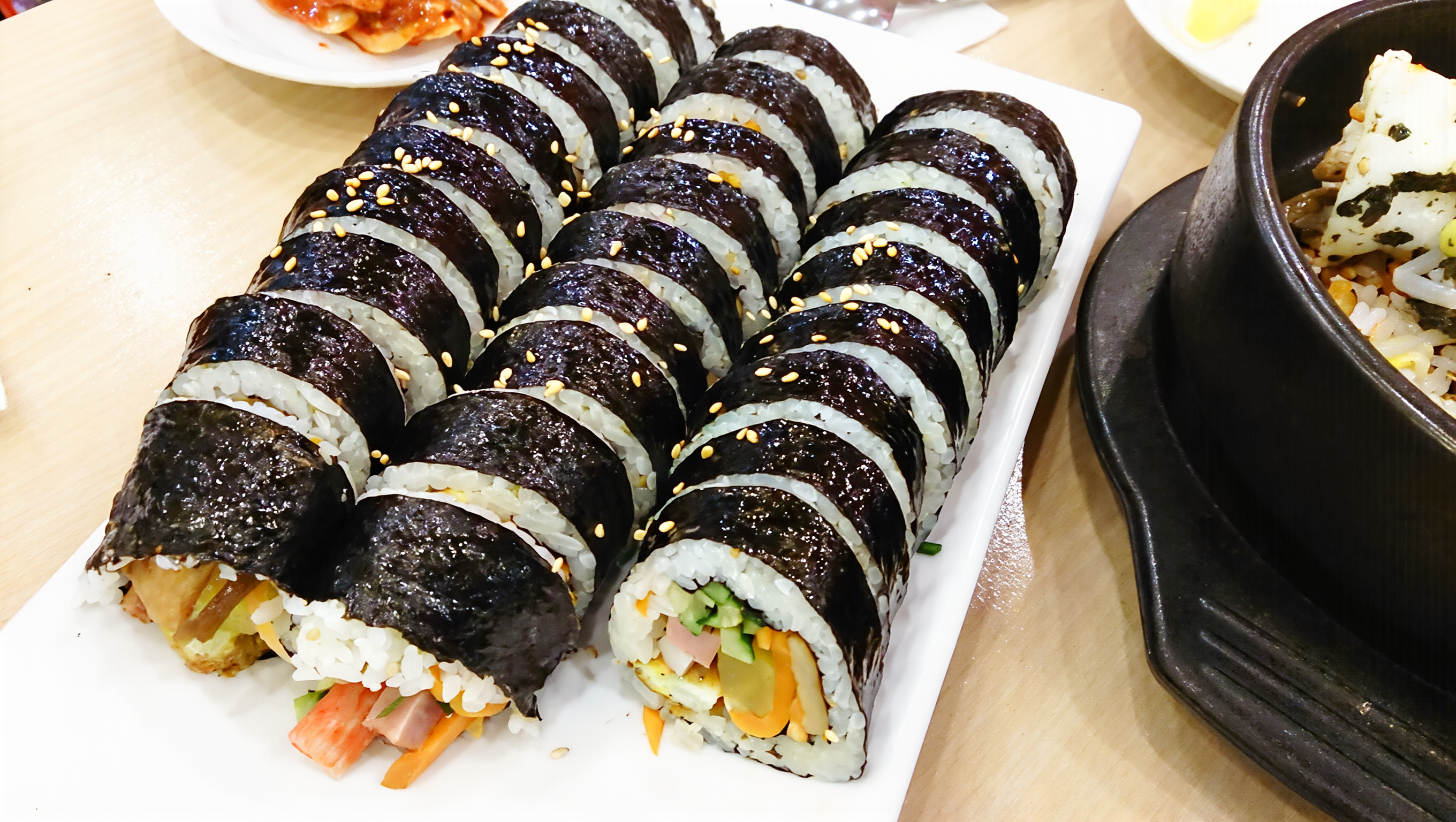 Bright plate of sliced Korean gimbap rolls with sesame seeds