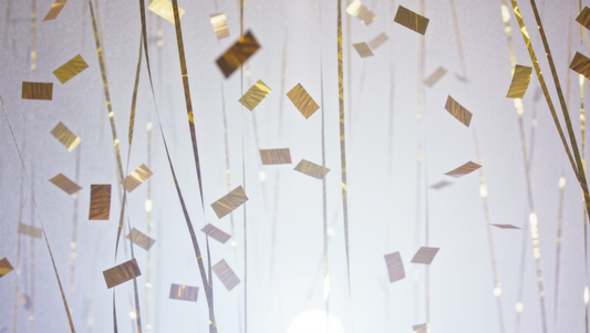 Golden confetti drifting through bright stage light haze, evoking a music awards celebration