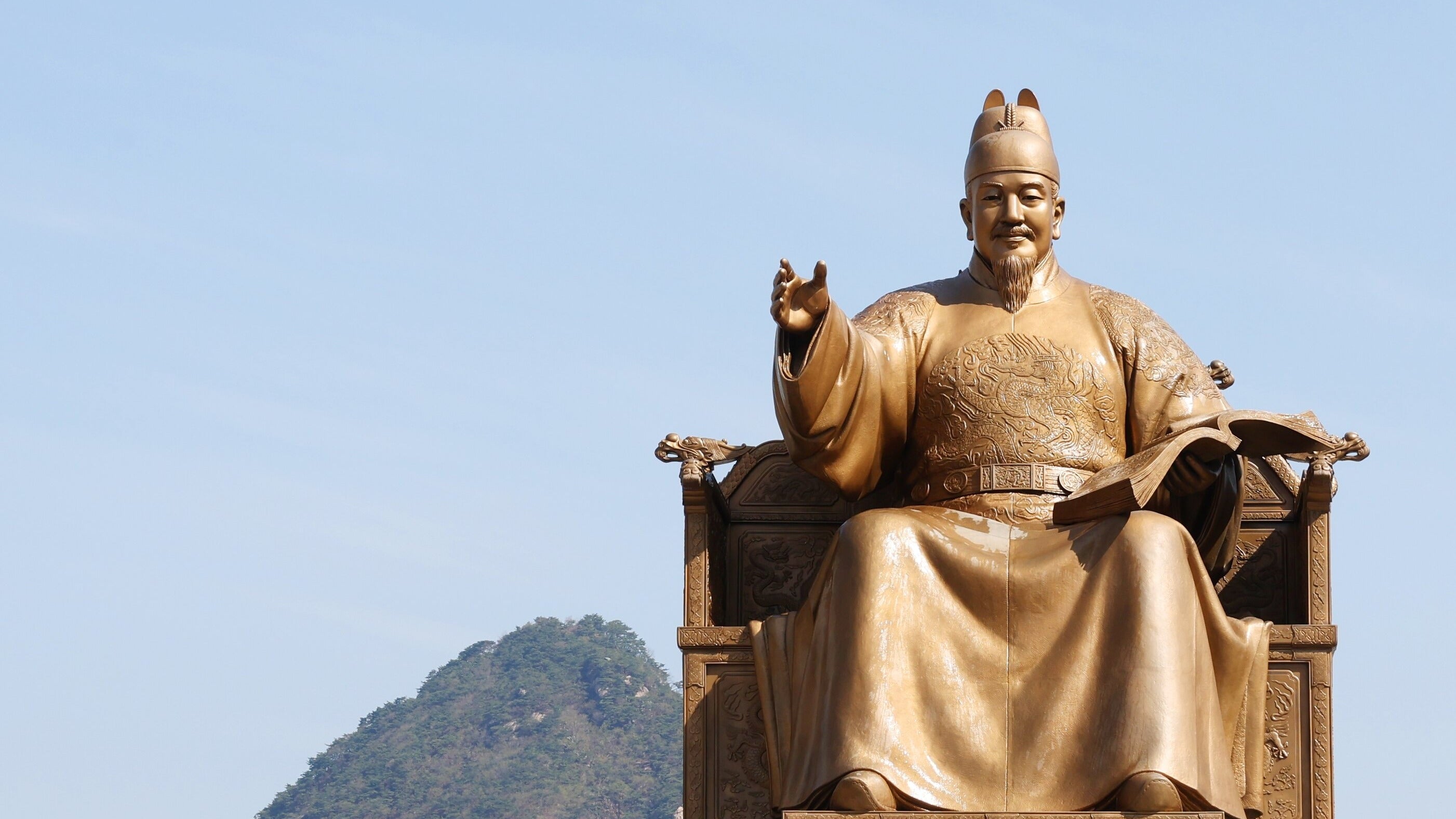 Hangul Day landmark: the gilded King Sejong statue in Gwanghwamun Square under a clear blue sky with Bugaksan behind