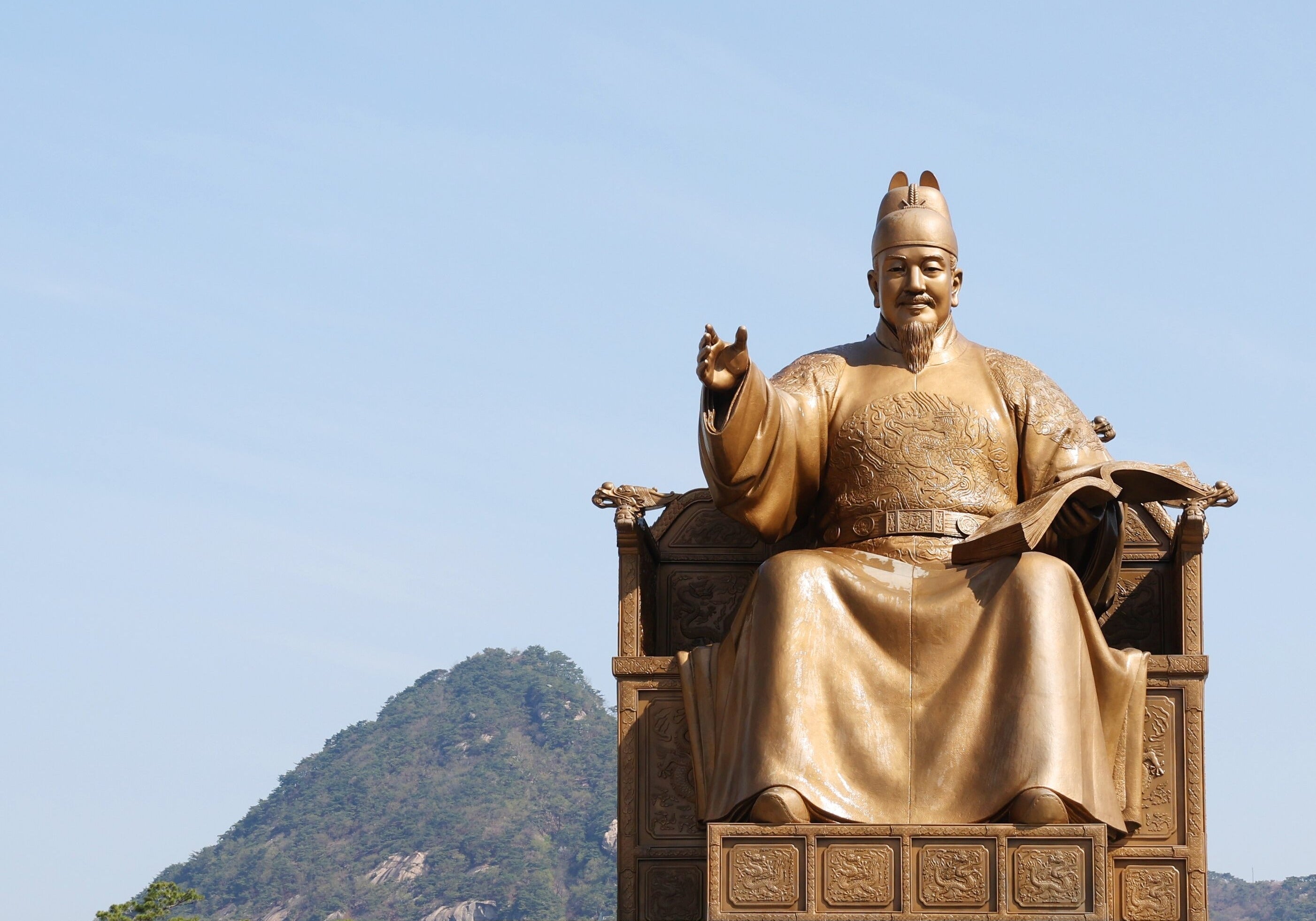 Hangul Day landmark: the gilded King Sejong statue in Gwanghwamun Square under a clear blue sky with Bugaksan behind