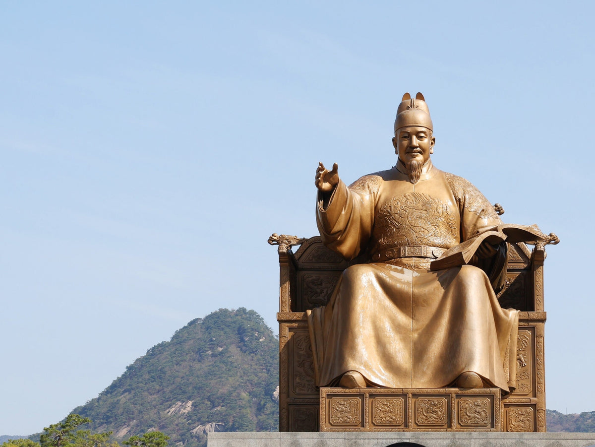 Hangul Day landmark: the gilded King Sejong statue in Gwanghwamun Square under a clear blue sky with Bugaksan behind