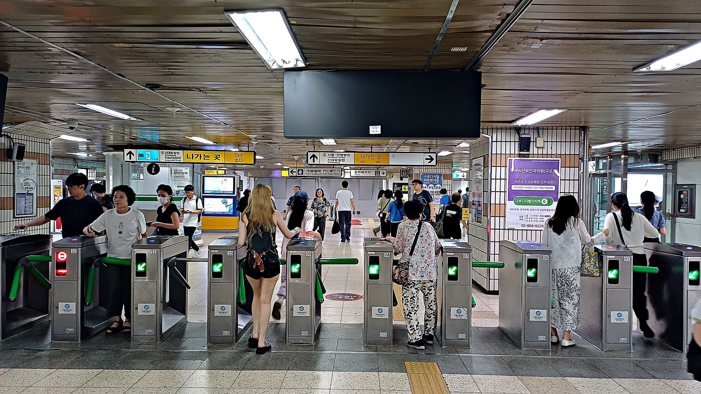 Seoul subway fare gates at Guro Digital Complex Station, riders tapping transit cards on a busy day