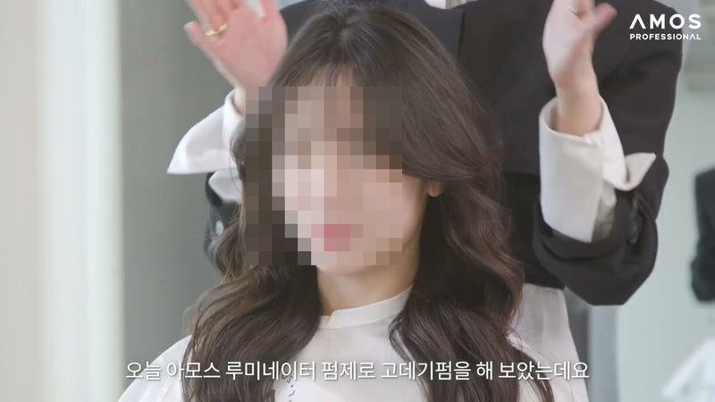 Long, soft Korean perm S-waves with face-framing layers on a client in a salon chair (Amos Professional Official YouTube)