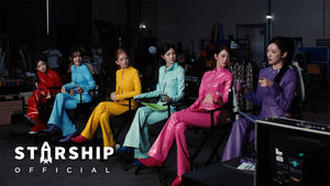 IVE's six members in colorful vinyl hero suits on a film set in the Looks Can Kill music video