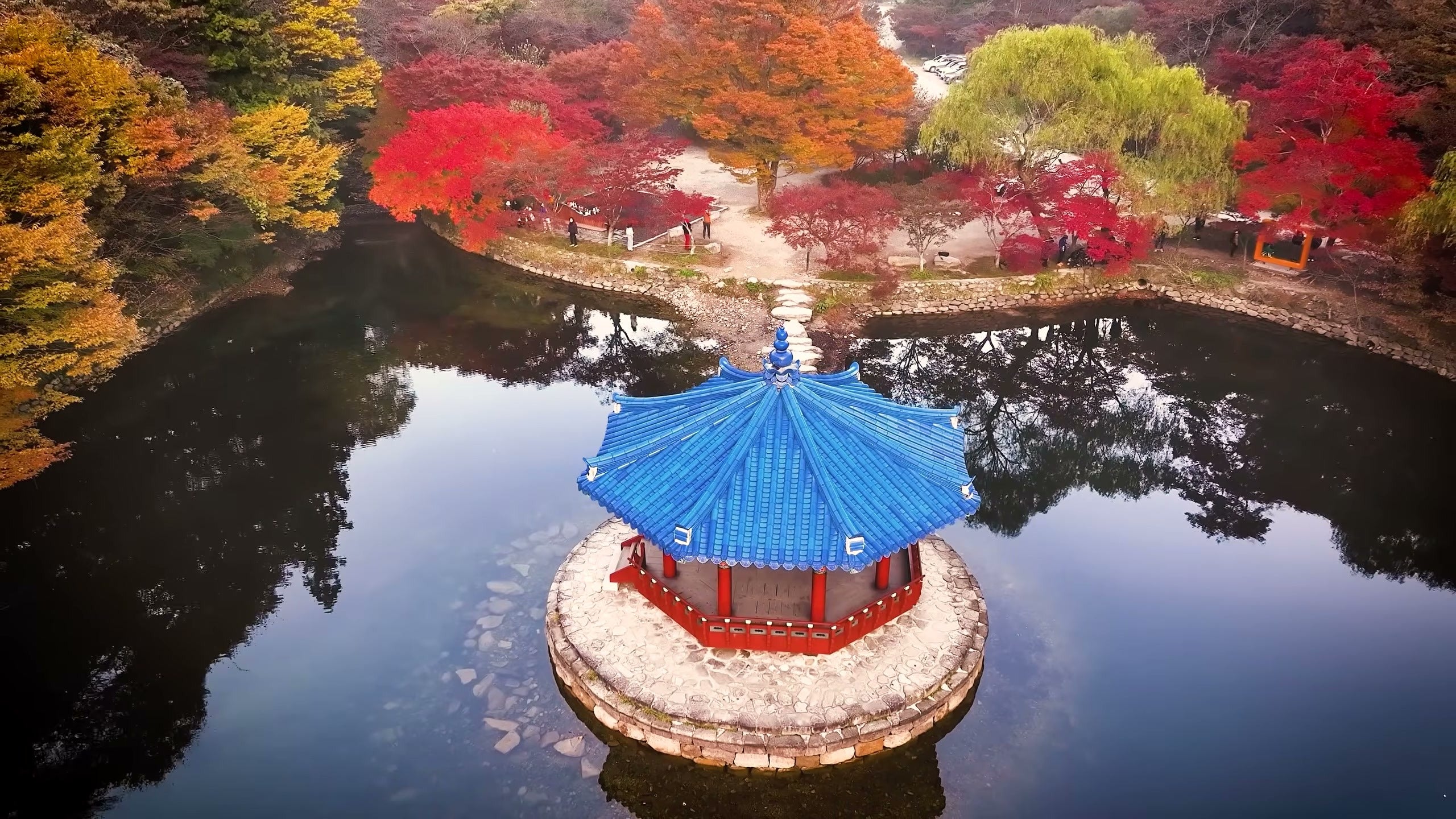 Naejangsan's blue-roofed Uhwajeong pavilion on its pond, ringed by red and orange maples (Jeongeup City Official YouTube)