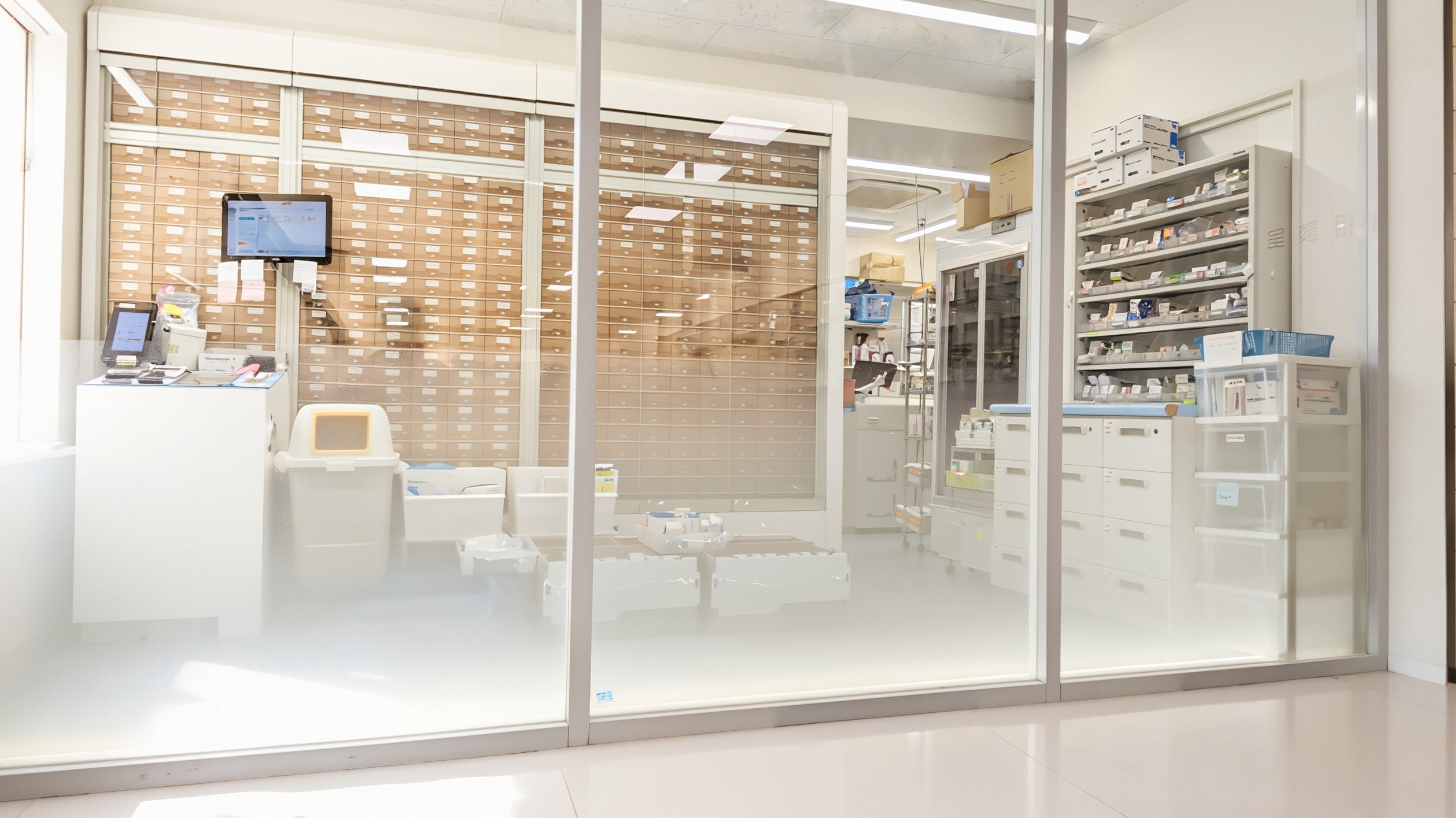 Pharmacy in Korea: a bright, modern dispensary behind glass with rows of drawers in clear morning light