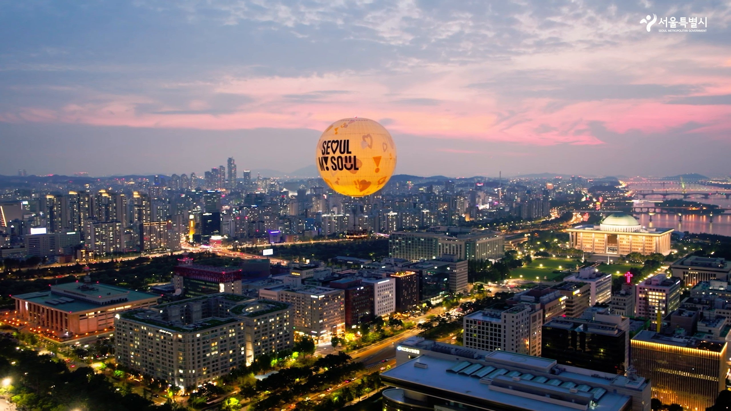 日落时分首尔之月在汝矣岛上空发光，下方是国会议事堂圆顶和汉江 (VisitSeoul TV Official YouTube)