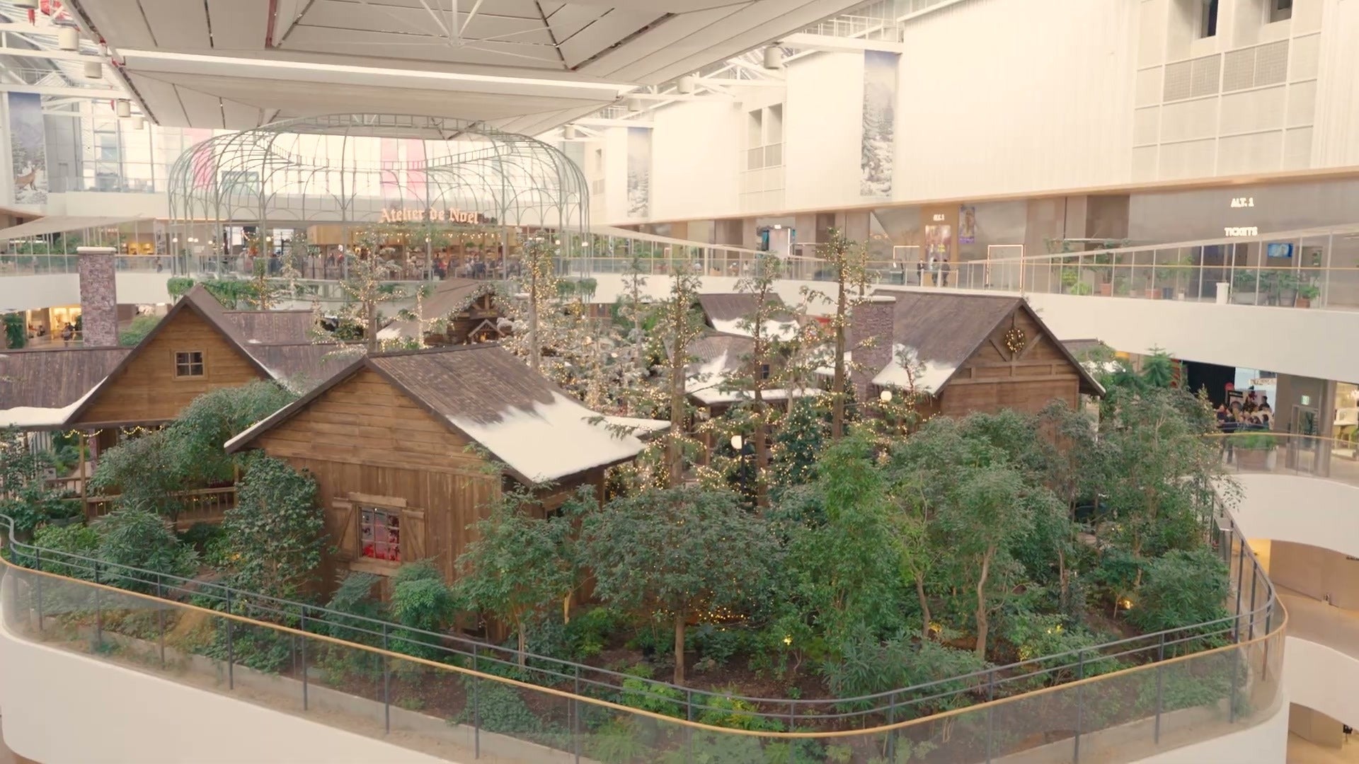 上から見たザ現代ソウルの2025年クリスマスビレッジ。5階の屋内庭園に並ぶ雪屋根のコテージと松の木々