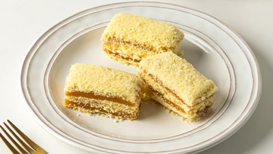 Changeok pumpkin injeolmi cut into bars on a white plate, sweet pumpkin rice cake coated in castella crumbs